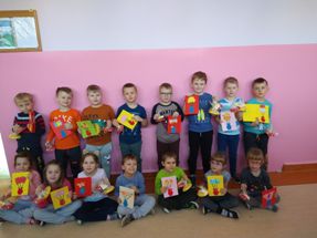 dzieci z klasy 0 a, ustawione w dwóch rzędach, trzymają w rękach prezenty i laurki dla babć i dziadków