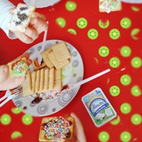 Uczniowie prezentują przygotowane przez siebie kolorowe kanapki. Krakersy są na talerzu